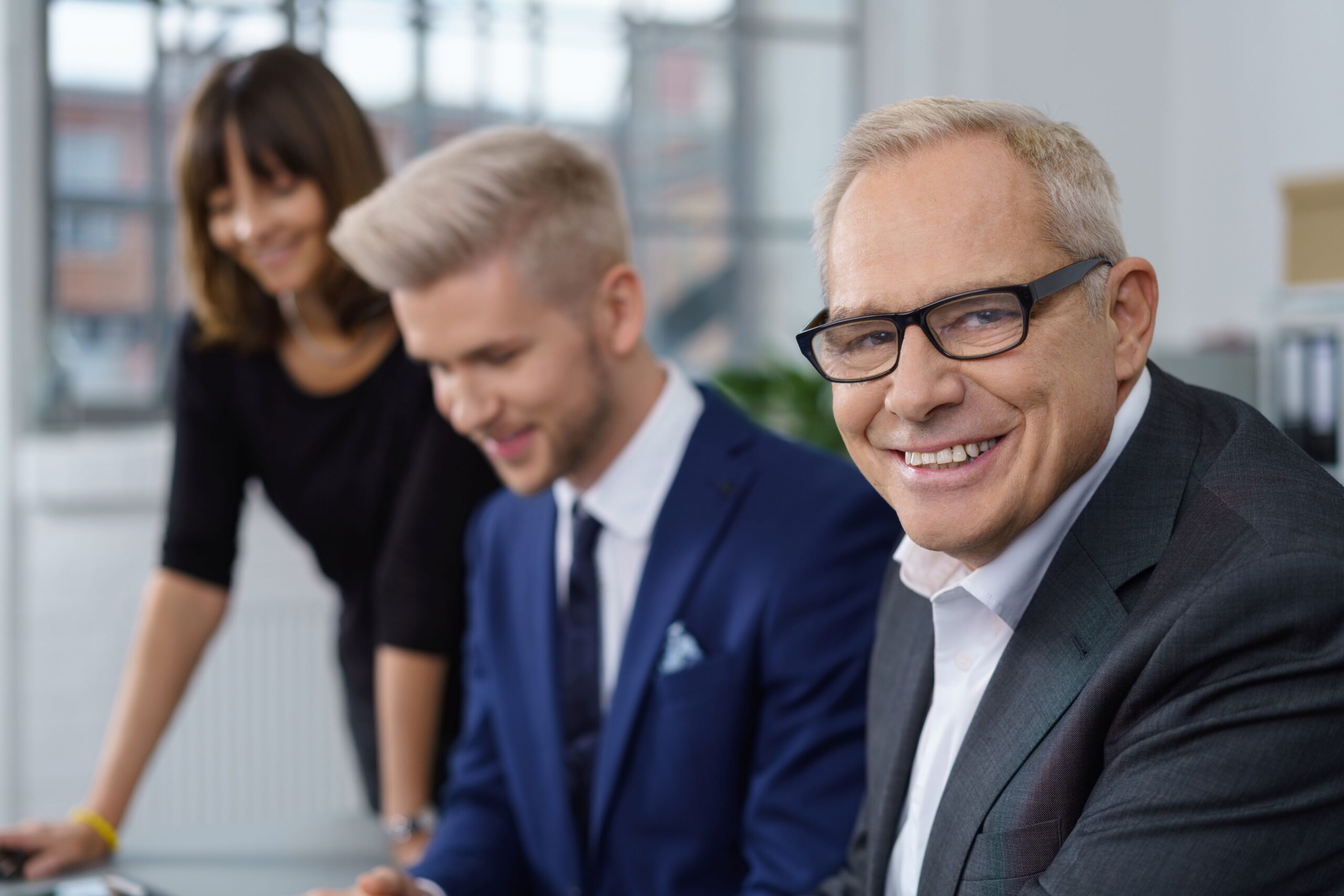 Führungskraft im Büro mit Team steht für strategische Entscheidung zugunsten von Compliance E-Learning