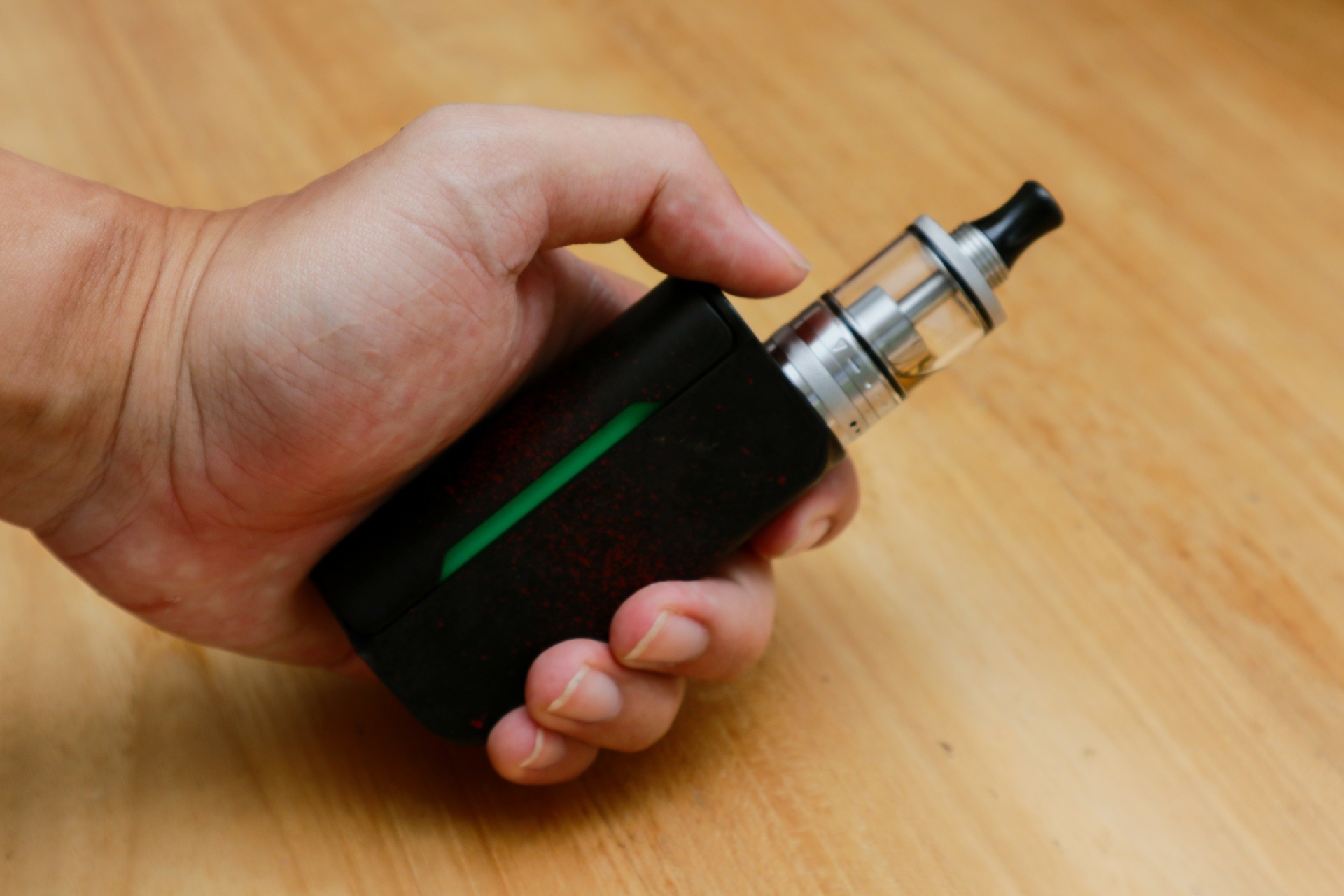 Hand hält elektronische Dampfe auf Holztisch | Elf Bar Elfa