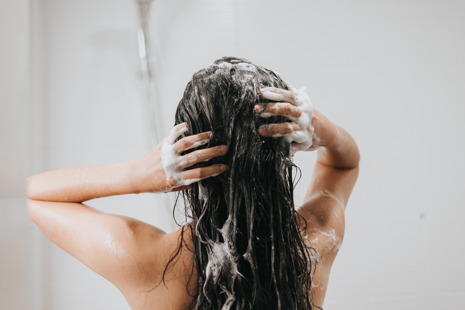 Frau wäscht sich die Haare unter der Dusche | Extensions